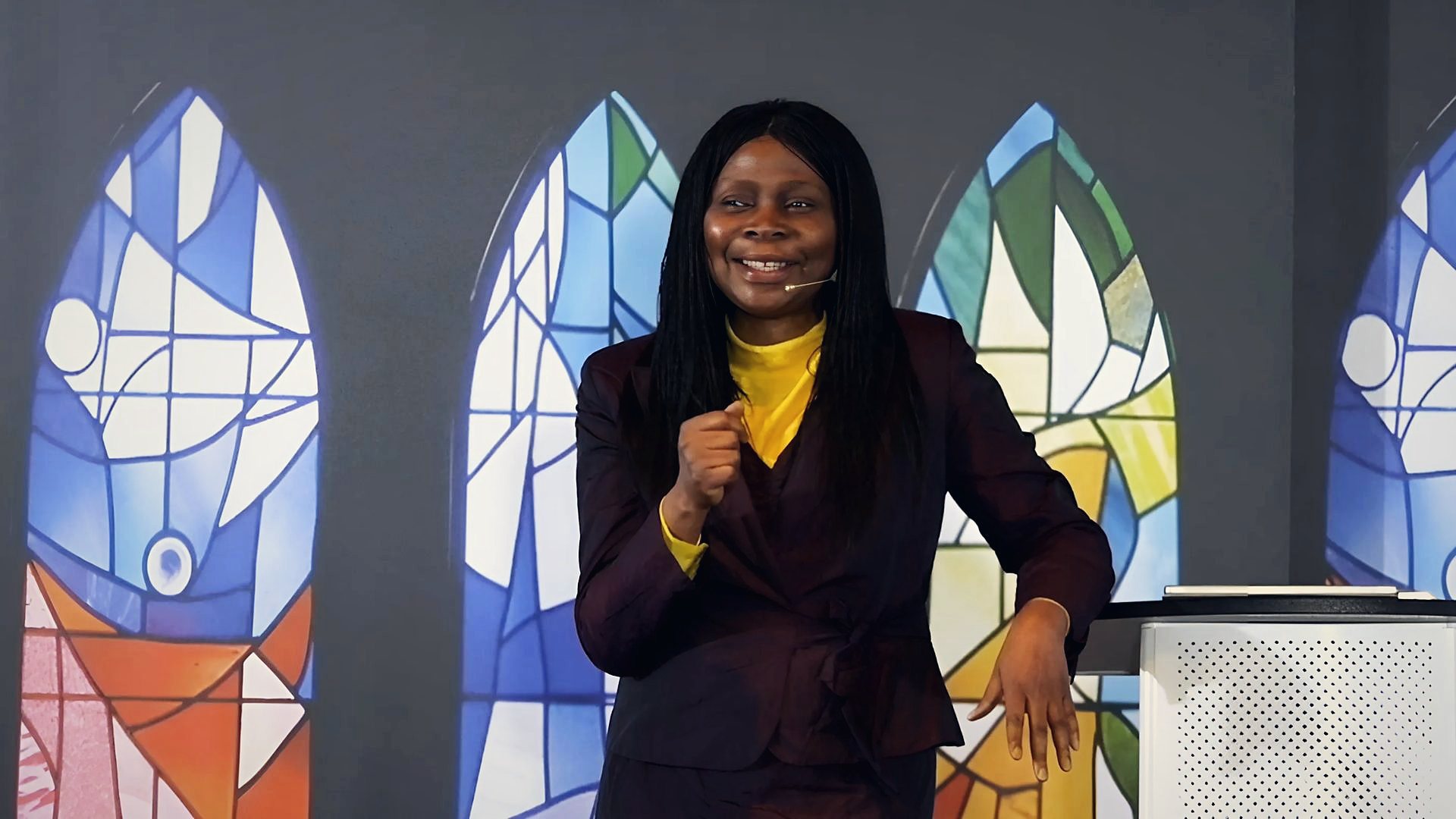 Pasteure Bola Ogedengbe souriante devant les vitraux d'Abba House